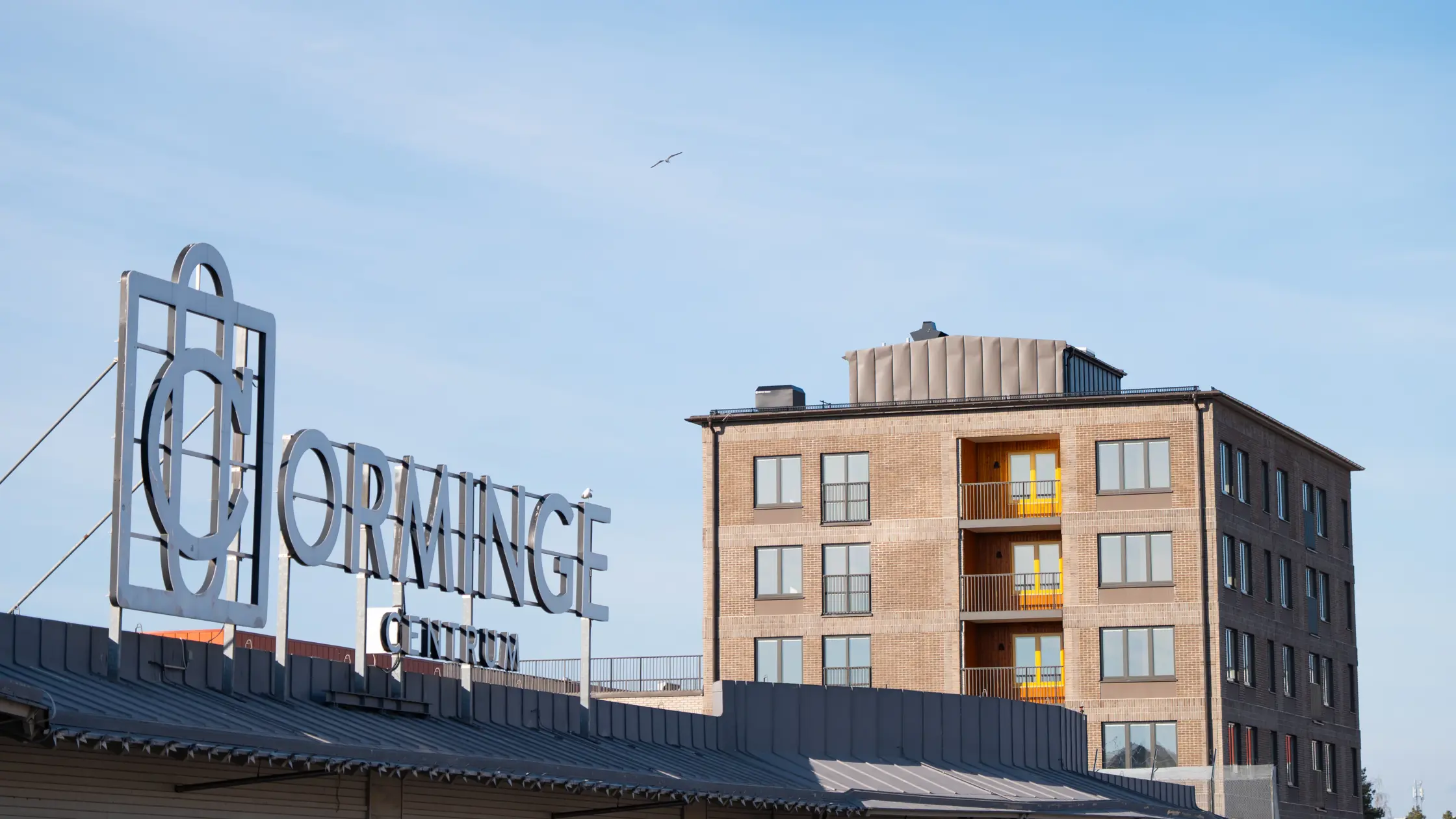 Skylt på tak i Orminge centrum med texten Orminge.